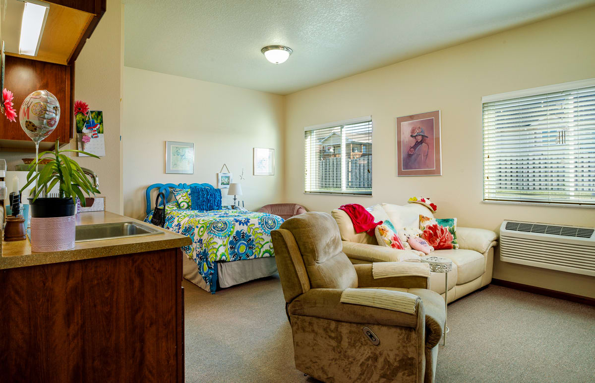 A cozy mixed-use room featuring a bed and living area with a sofa and armchair.
