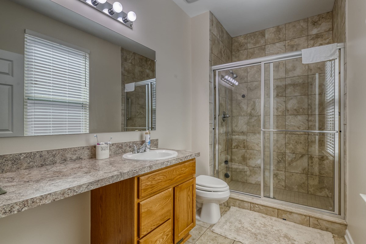 A modern bathroom featuring a glass-enclosed shower, vanity with sink, and a toilet.