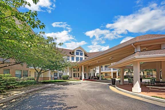 A welcoming building entrance with a driveway and a clear blue sky overhead.