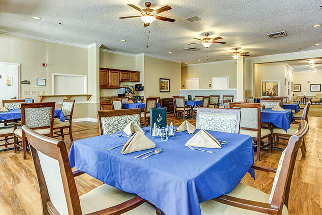 A neatly arranged dining area with blue tablecloths and elegant place settings.
