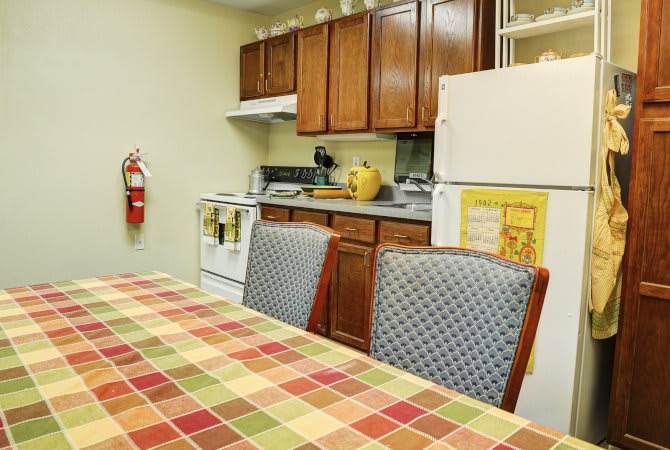 A cozy kitchen with a checkered tablecloth on the dining table and wooden cabinets.