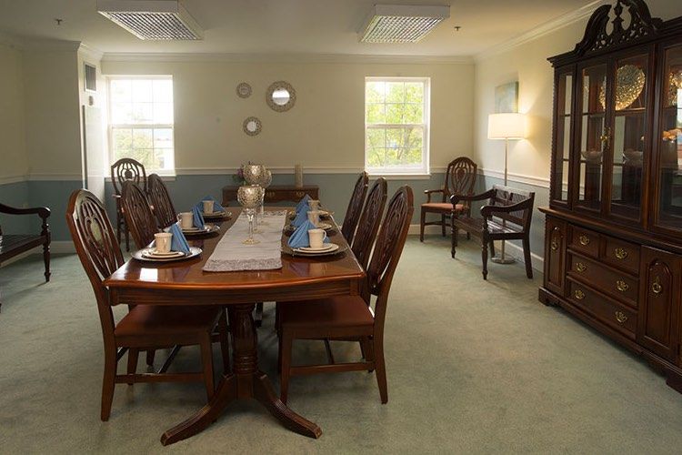 A well-furnished dining room with a long wooden table set for a meal, surrounded by elegant chairs and decorated with home dcor accents.