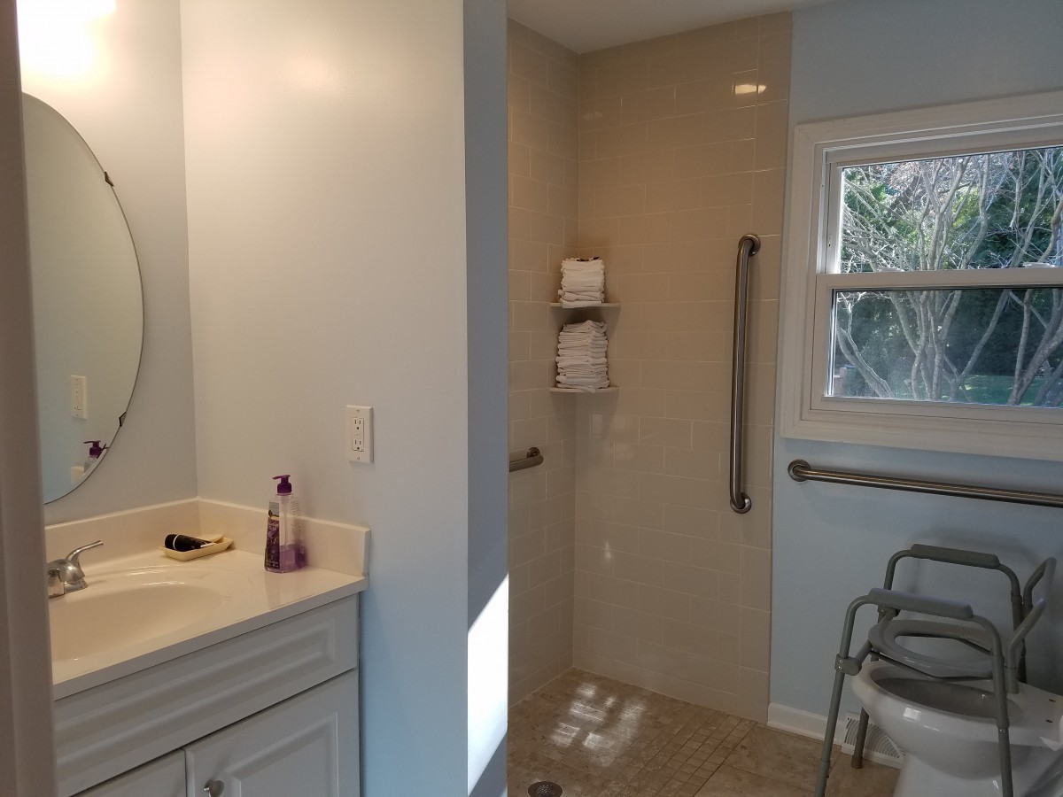 An accessible bathroom featuring a walk-in shower with grab bars and a vanity sink.