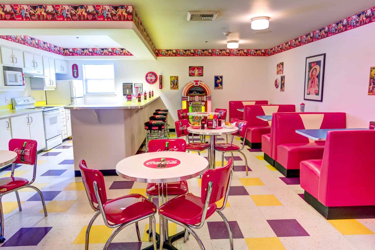 A classic 1950s-style diner with red seating, a jukebox, and colorful floor tiles.