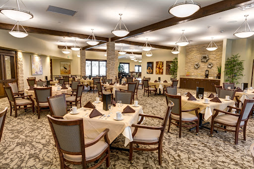 A spacious and elegantly designed dining room ready for guests, featuring well-set tables and tasteful decor.