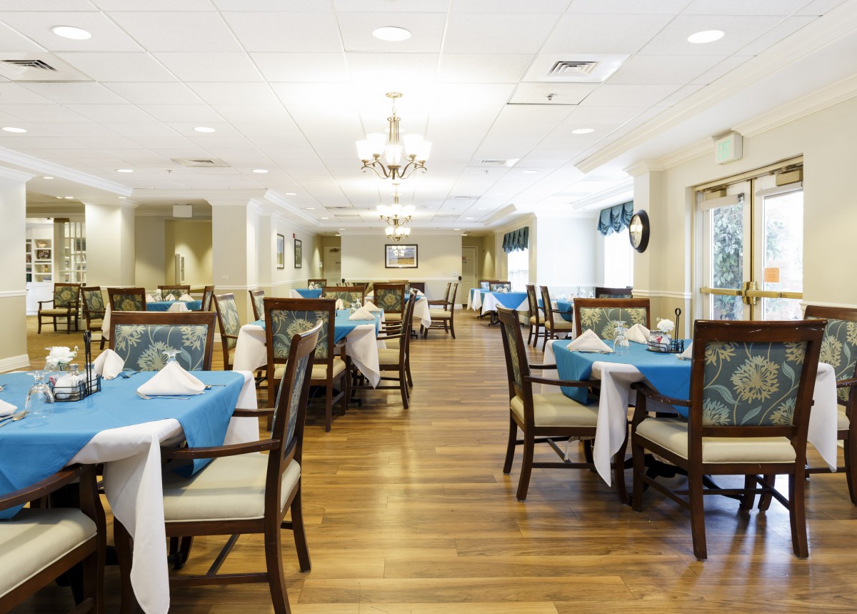 A well-lit restaurant dining area with tables set and blue tablecloths.