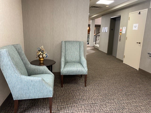 A quiet office lobby with two chairs and an elevator.