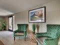 A cozy hallway with green chairs and a landscape painting.