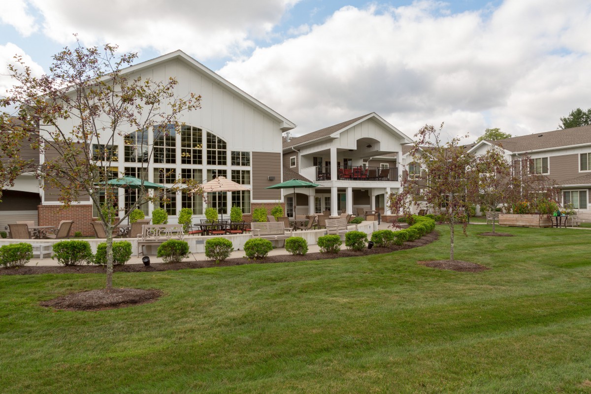 A modern residential building with large windows and a well-maintained lawn.