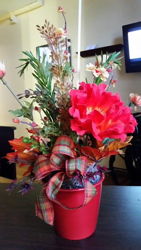 A vibrant floral arrangement featuring a large red flower and various greenery, beautifully designed for home decoration.