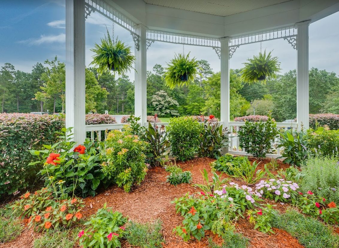 A beautiful garden with vibrant flowers and hanging plants under a gazebo.