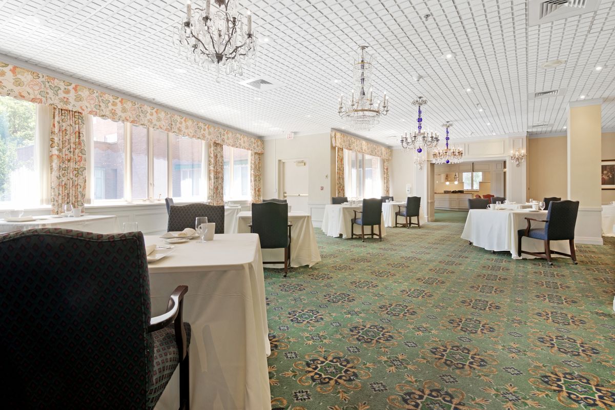 A bright and elegant dining room with chandeliers and neatly arranged tables.