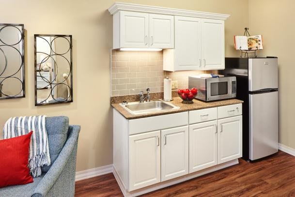 A compact kitchen area with white cabinetry and a sink, featuring a microwave on the countertop.
