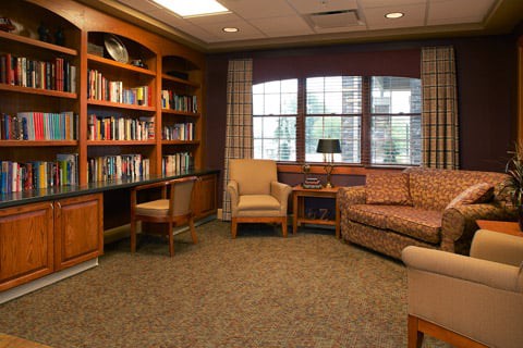 A cozy library corner with bookshelves, comfortable seating, and natural light.
