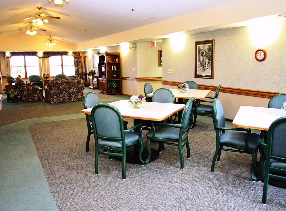 A well-lit indoor dining area with tables and chairs, featuring a cozy carpeted floor.