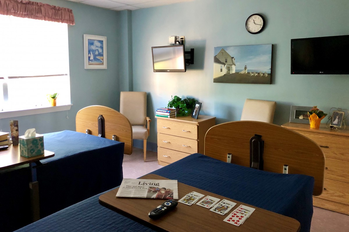 Hospital room with two beds, a television, and a window.