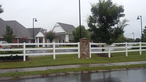 A charming residential house with a white fence, set against a backdrop of rainy clouds.