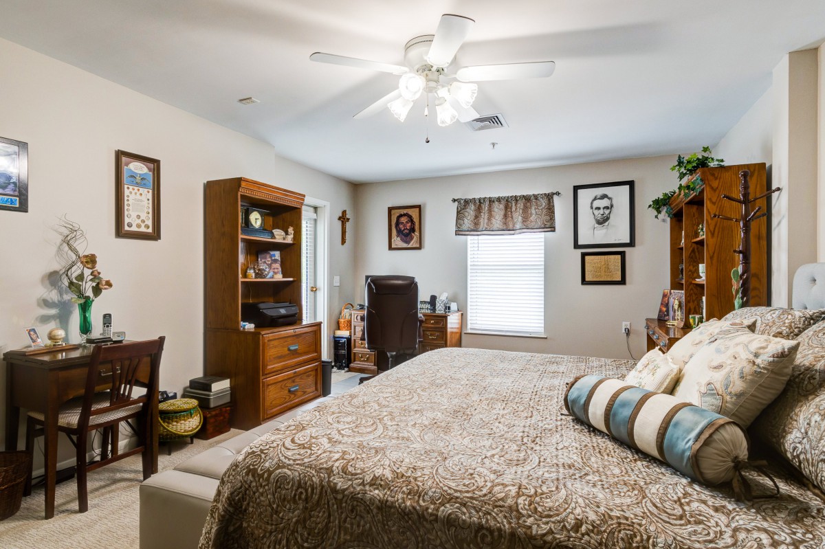 A cozy bedroom featuring a bed, home office setup, and decorative elements.
