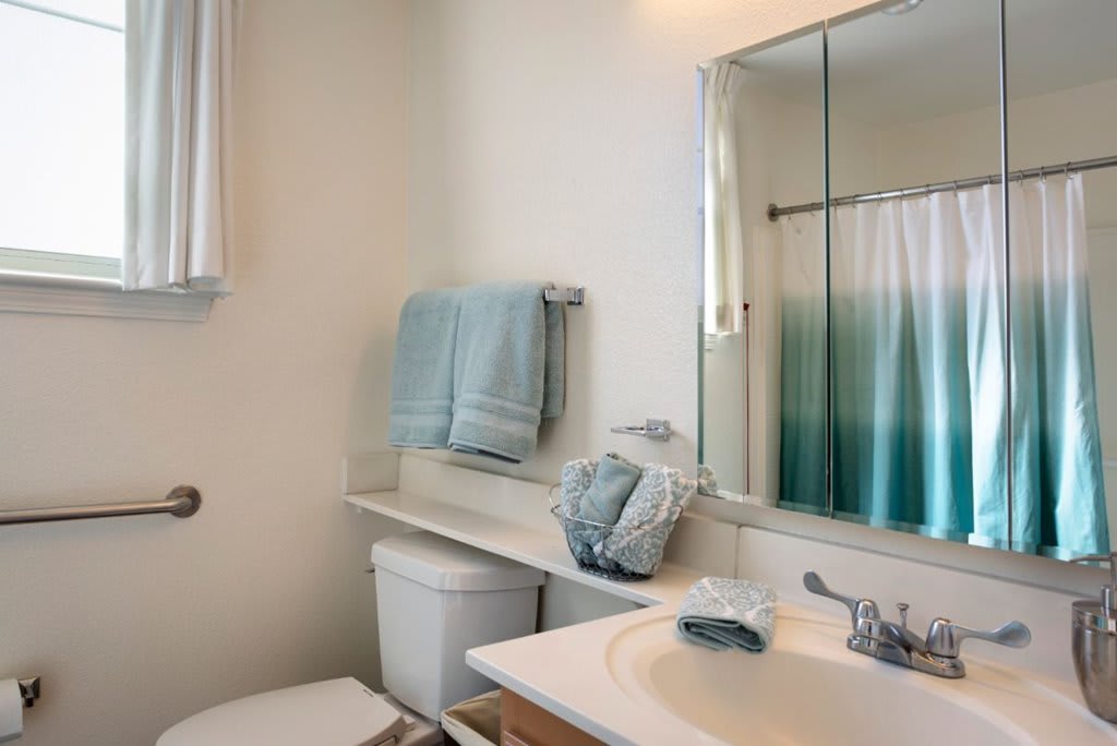 A neatly arranged bathroom with light blue towels and a gradient shower curtain.