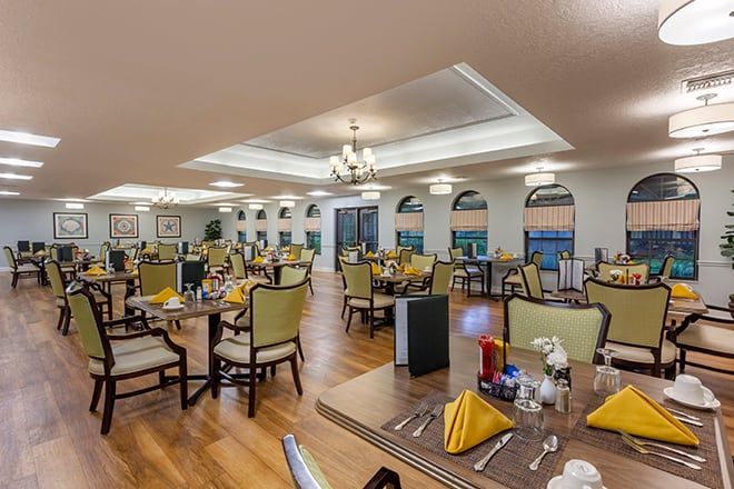 An elegant restaurant dining room with neatly arranged tables and chairs, featuring warm lighting and tasteful decor.
