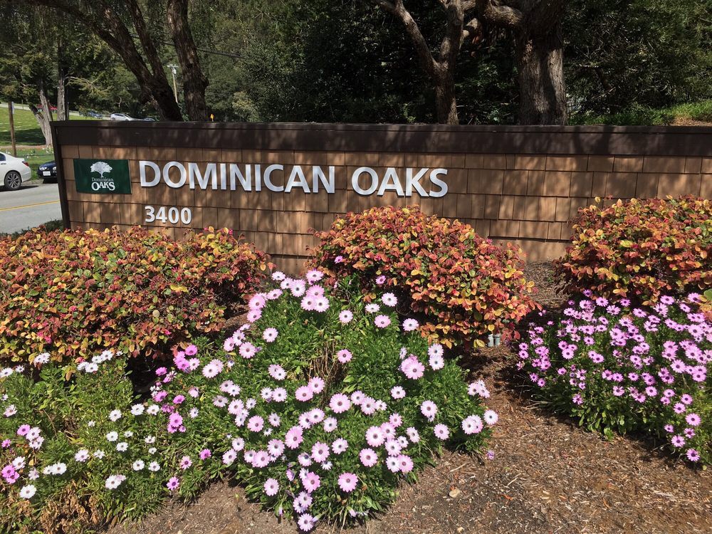 Entrance sign for Dominican Oaks surrounded by flowers and landscaping.
