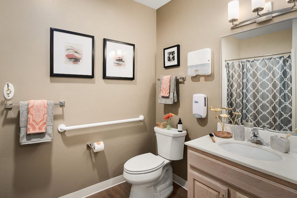 A modern bathroom with a toilet, sink, and decorative elements such as framed art and a towel rack.
