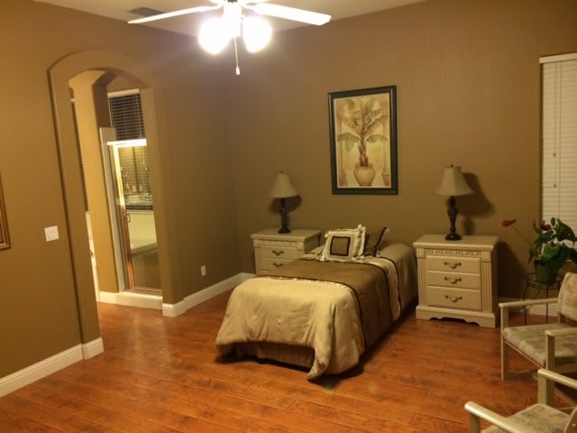 A cozy bedroom with a single bed, nightstands, and warm lighting.