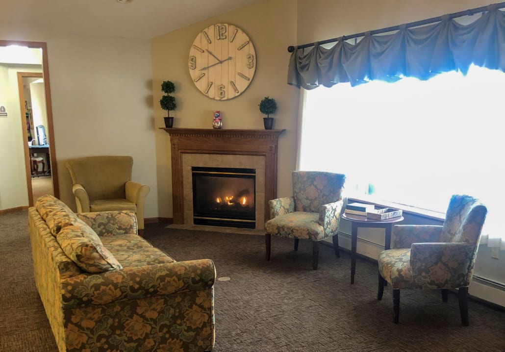 A cozy living room with a fireplace and a large wall clock.