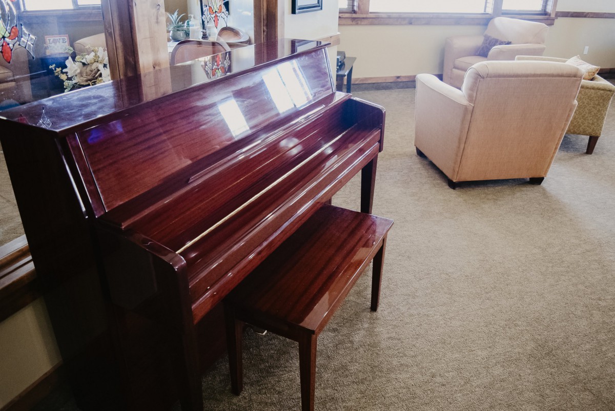 A polished upright piano in a cozy living room setting.