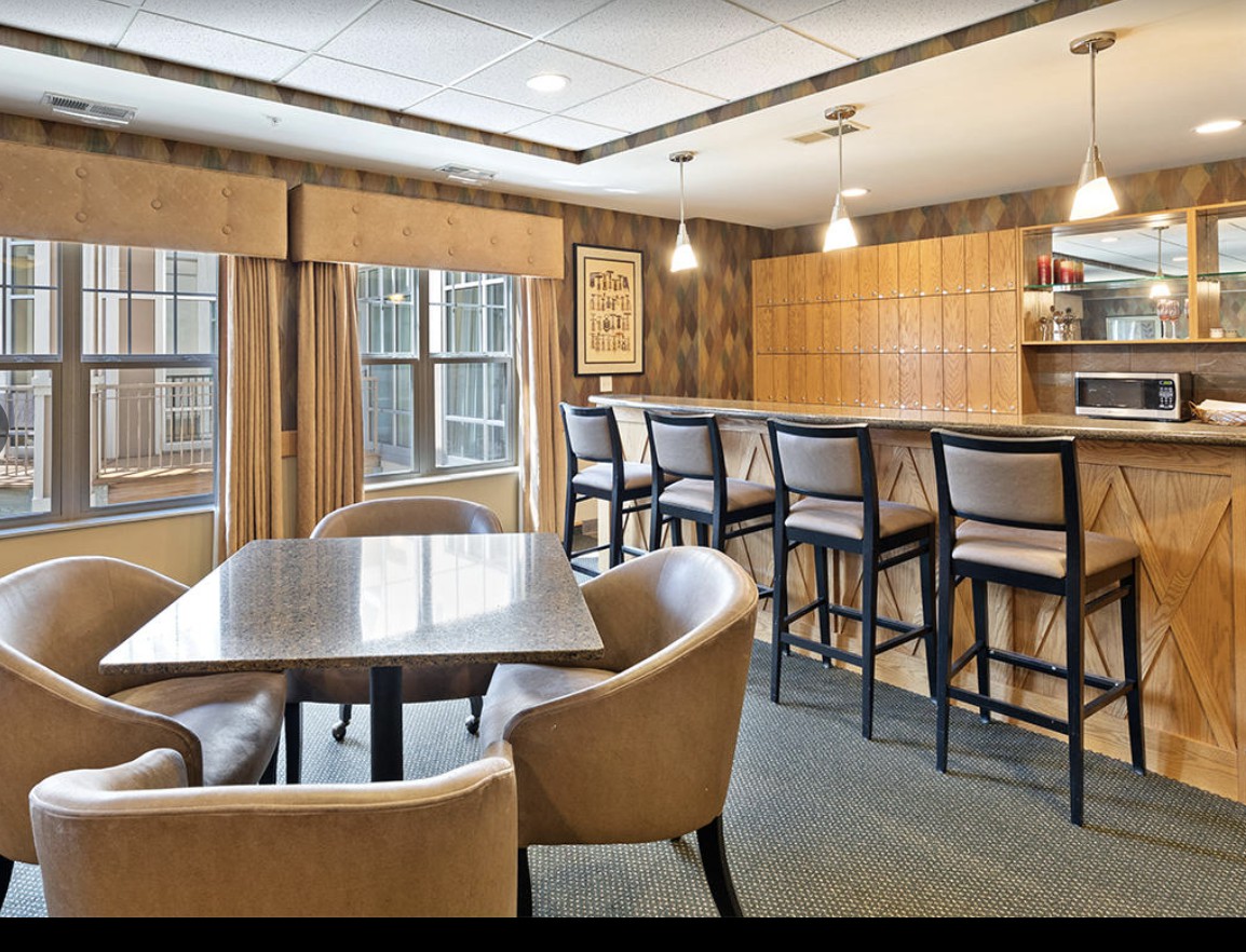 A modern kitchen with a bar and dining area featuring wood paneling and stylish lighting.