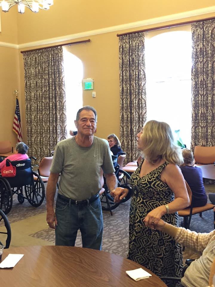 A casual gathering takes place in an indoor setting with people interacting, some seated in wheelchairs.