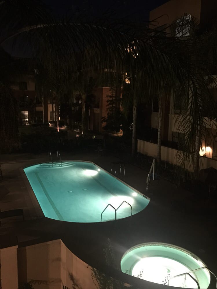 A serene outdoor swimming pool illuminated at night in a residential area.