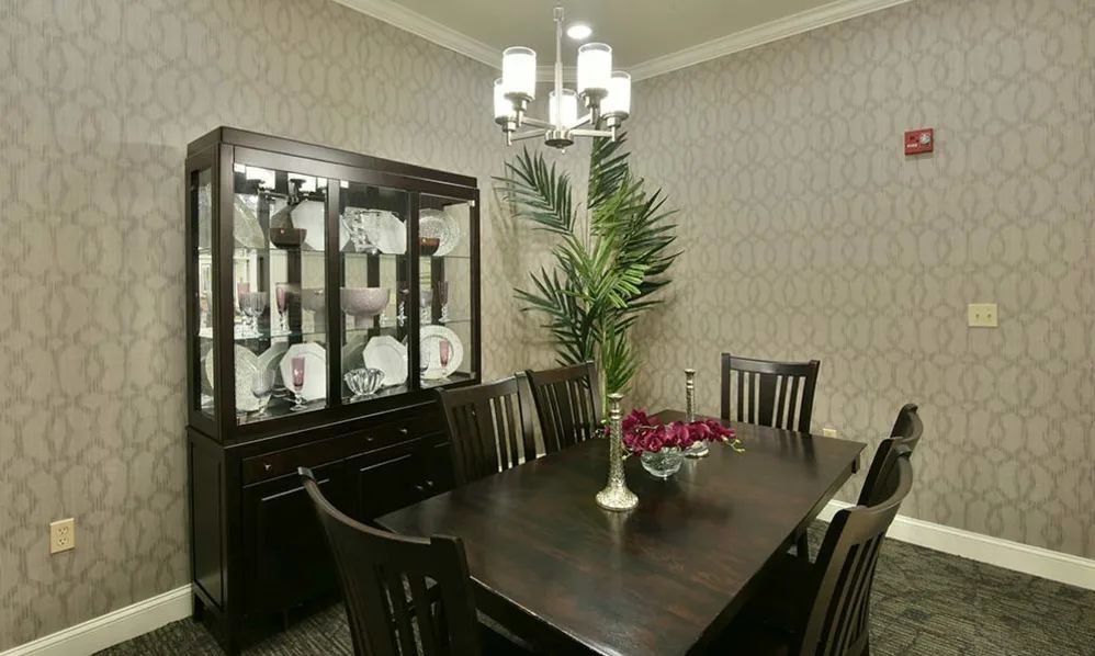 A stylish dining room with a dark wooden table, chairs, and a decorative cabinet.