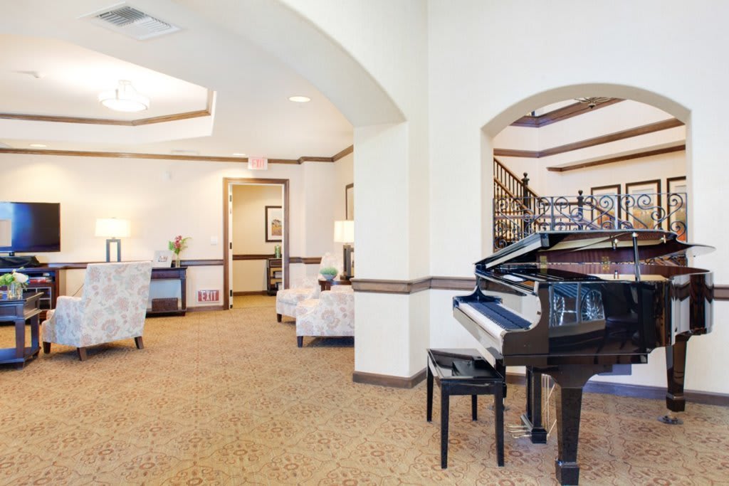 A spacious living area with a grand piano and comfortable seating, featuring elegant decor.