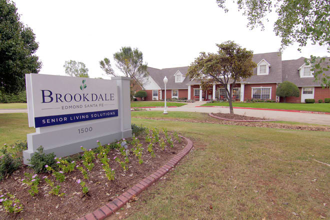 A residential building with a sign reading 'Brookdale' amidst a well-maintained lawn and trees.