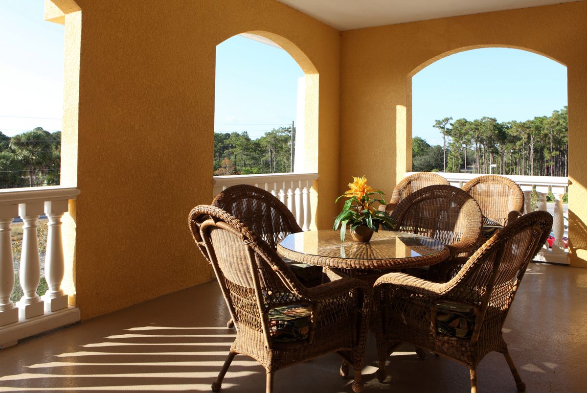 A sunny patio with wicker furniture and a decorative plant.