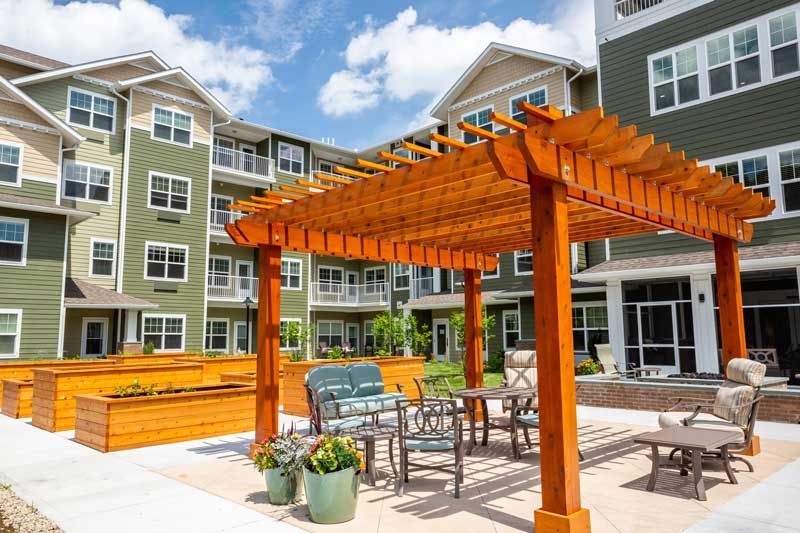 A modern apartment complex featuring an outdoor seating area with a wooden pergola.