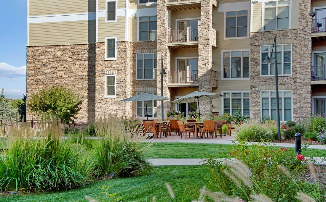 A modern apartment building with a landscaped garden and outdoor seating area.