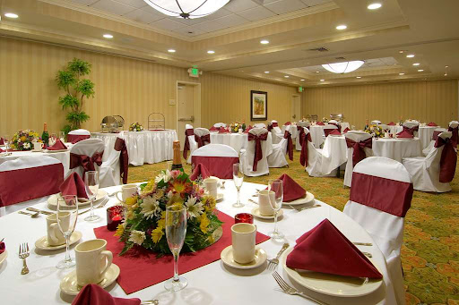 A beautifully arranged dining space set for an elegant event, featuring white tablecloths and red accents.