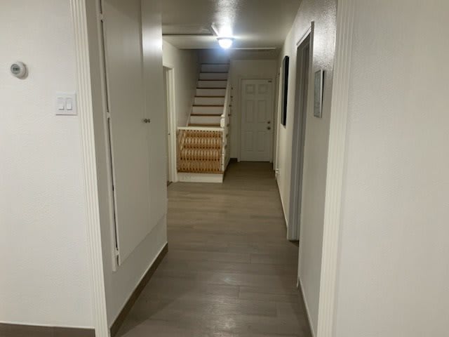 A modern hallway with wooden flooring leading to a staircase.