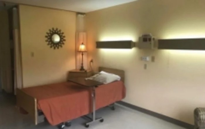 A hospital room with a single bed and warm lighting.