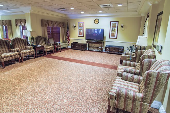 An empty waiting room with arranged chairs and a television.