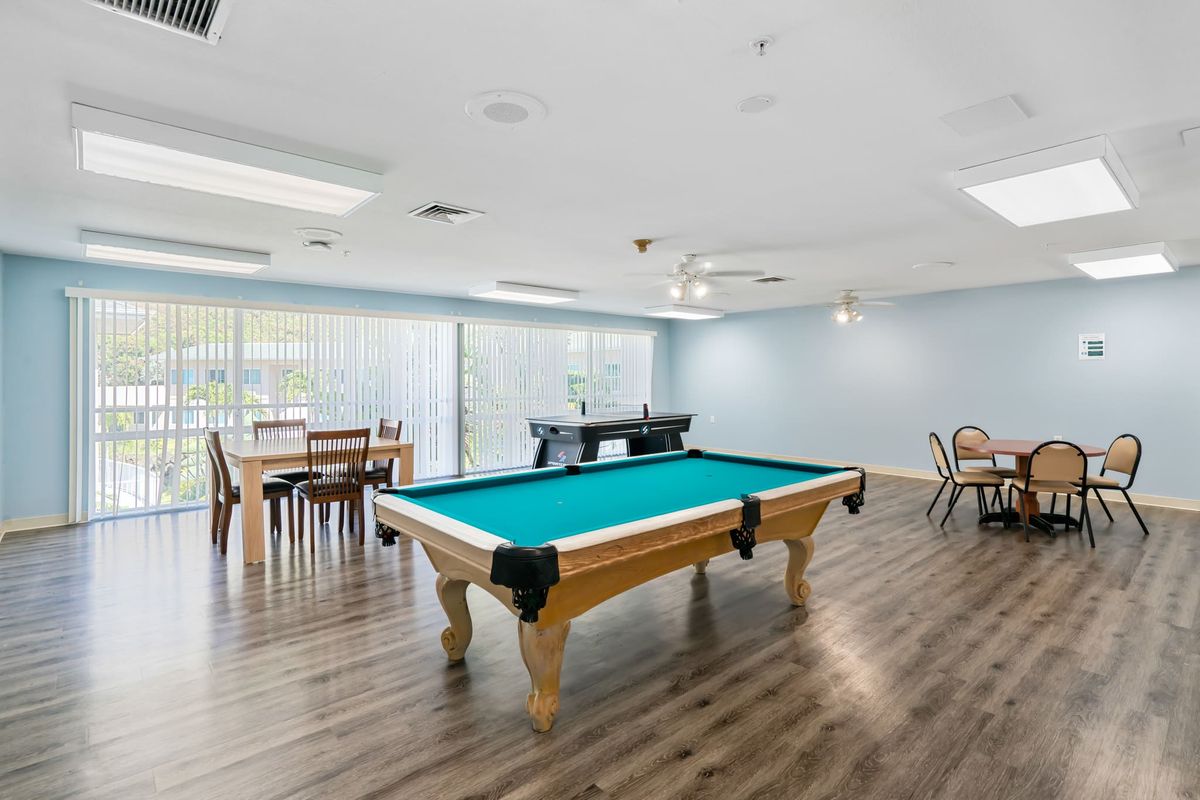 A spacious game room featuring a pool table and seating area with natural light.
