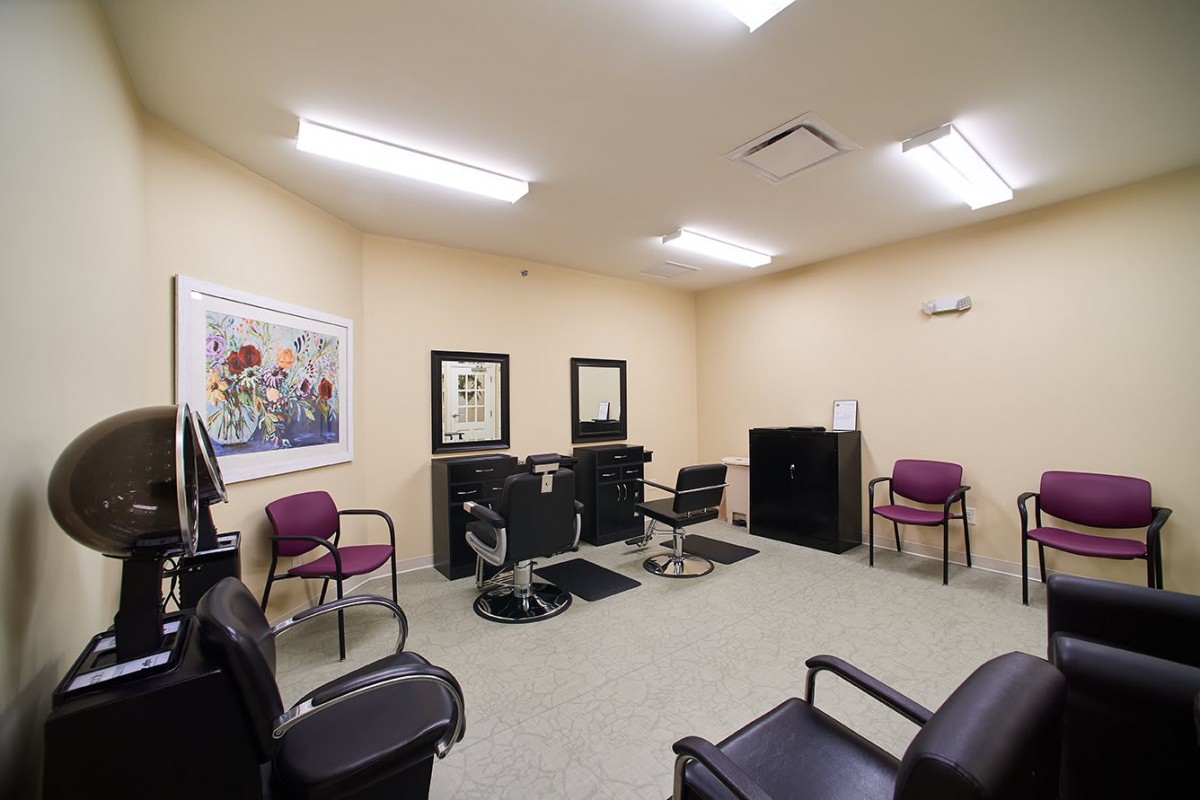 An interior view of a barbershop with chairs, mirrors, and a waiting area.