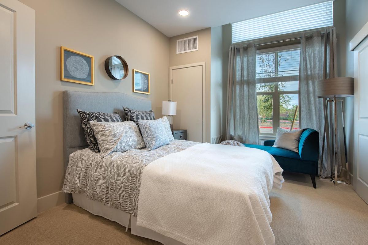 A cozy and well-decorated bedroom featuring a comfortable bed, elegant decor, and a large window providing natural light.