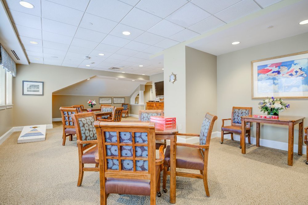 A modern, well-lit dining area with wooden chairs and tables on a carpeted floor.