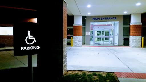 Main entrance with accessible parking sign at night.