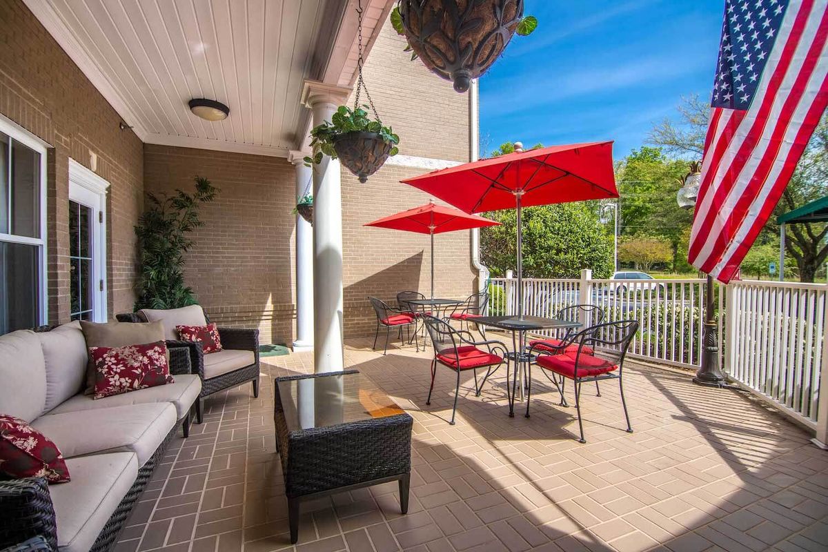 A cozy patio setting with red chairs and umbrellas, perfect for relaxing on a sunny day.