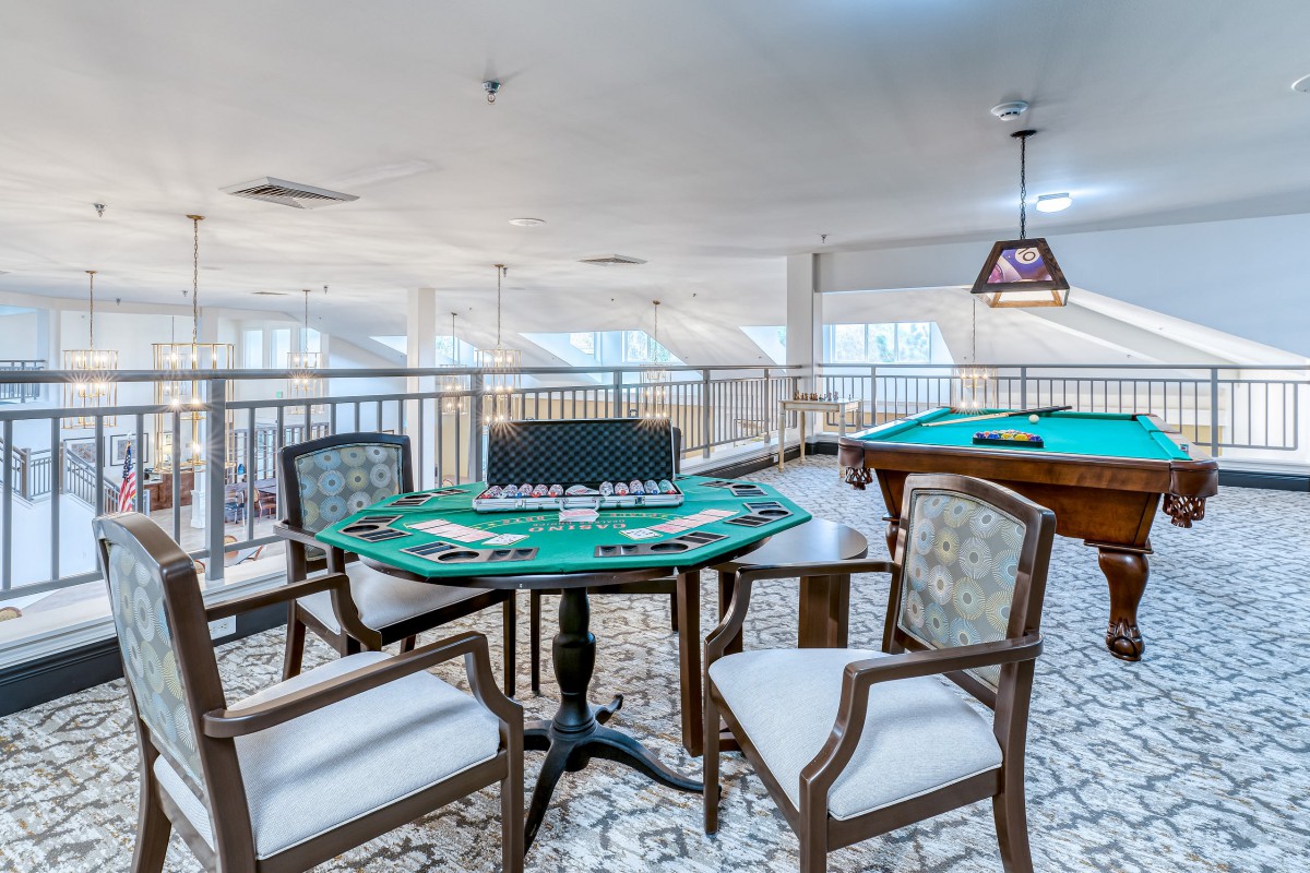 A stylish and well-lit game room featuring a poker table and a billiards table.