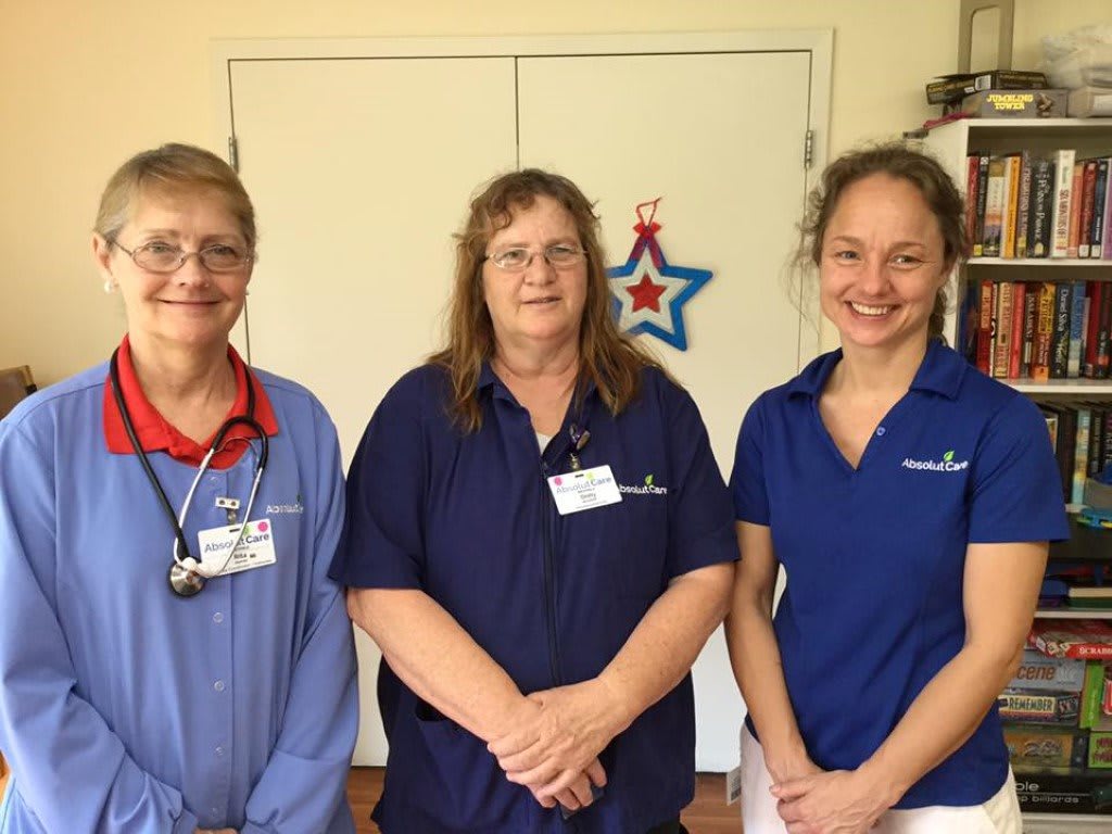 Three healthcare workers posing together indoors.